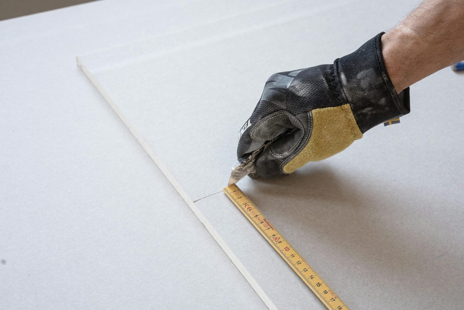 A gloved hand using a ruler for precise measurements in a construction project.